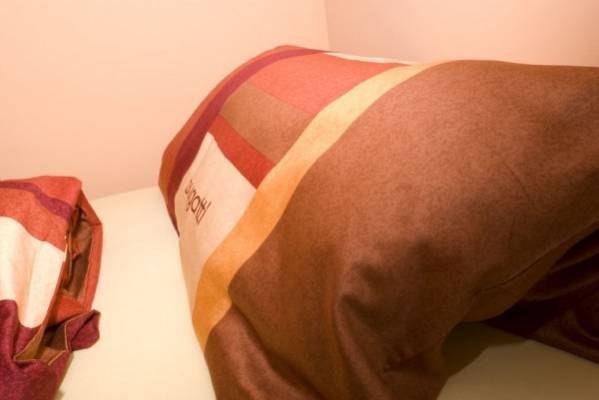 Zdjęcie przedstawia łóżko w pokoju EUROBAŁTYK Pokoje i Domki