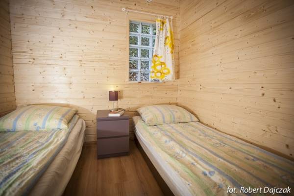 Zdjęcie przedstawia łóżko w pokoju - Domki drewniane DOMINIKA | Rewal (wypoczywaj nad morzem) 